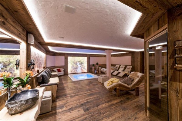 Luxusný wellness priestor s vírivkou a lehátkami na drevenej podlahe.