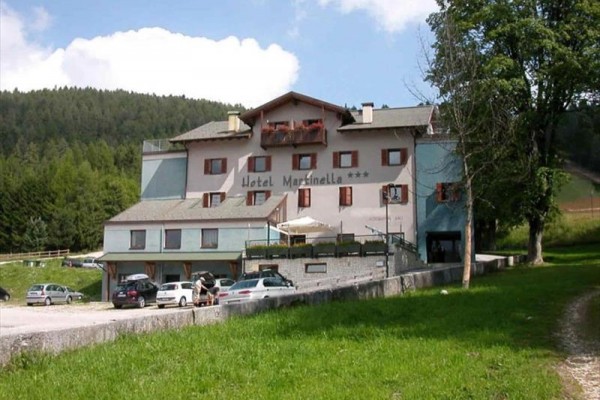 Hotel v horskej krajine s parkoviskom pred ním.  