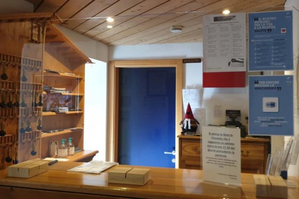 Recepcia s dreveným pultom, kľúčmi na stene a informačnými letákmi.