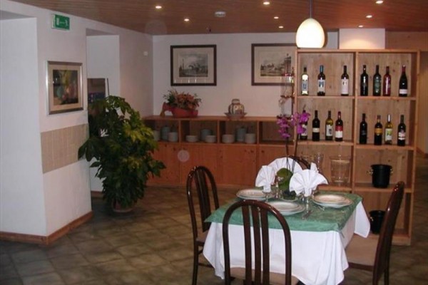 Elegantne prestretý stôl v reštaurácii s dreveným obložením a regálom s fľašami vína.