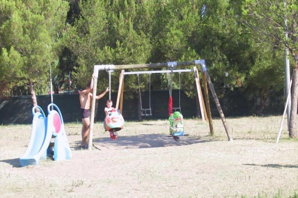 Konštrukcia hojdačiek a šmykľavka na detskom ihrisku s dospelým a dieťaťom.