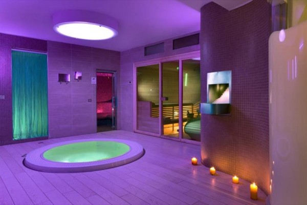 Luxusné spa s vírivkou, saunou a sviečkami pri fialovom osvetlení.