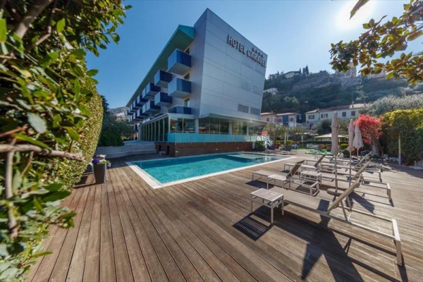 Moderný hotel s vonkajším bazénom a terasou obklopenou lehátkami.