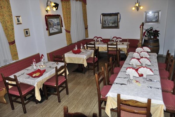 Reštaurácia s pripravenými stolmi, červeným čalúnením a žltými obrusmi.  