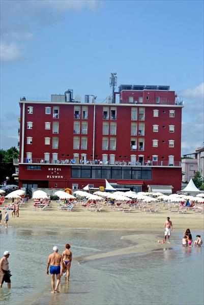 Hotel pri pláži s ľuďmi prechádzajúcimi sa v plytčine.