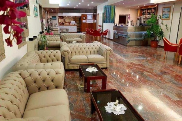 Elegantná hotelová lobby s béžovými pohovkami a drevenými konferenčnými stolíkmi.