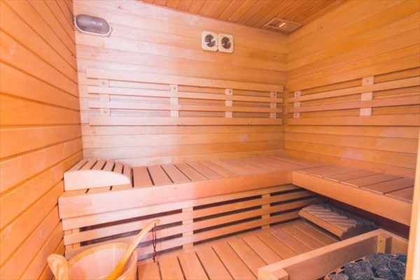 Drevená sauna s lavicami a vedrom na vodu.