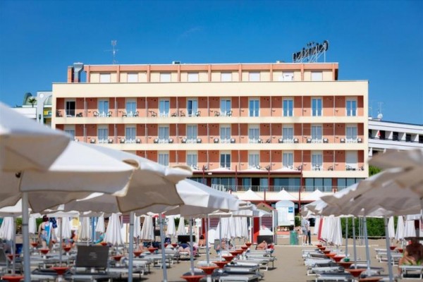 Pred hotelom sú rady lehátok a slnečníkov na pláži.