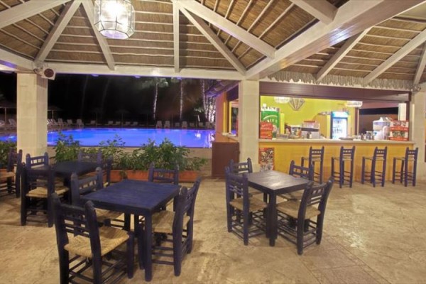 Vonkajší bar pri bazéne s drevenými stolmi a stoličkami.