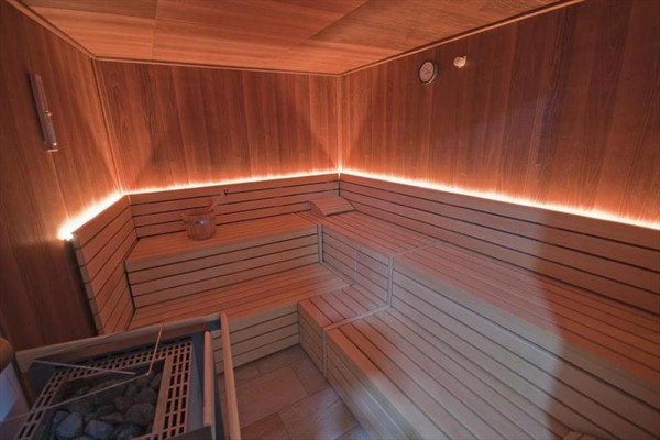 Drevená sauna s lavičkami a jemným osvetlením.  
