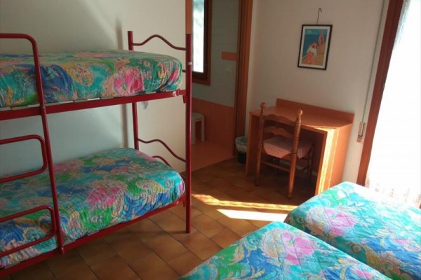 Izba s poschodovou posteľou a stolíkom, farebné obliečky.