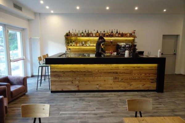 Moderný bar s dreveným pultom, kde personál pripravuje nápoj.