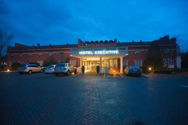 Vchod do hotela Executive s parkoviskom za súmraku.