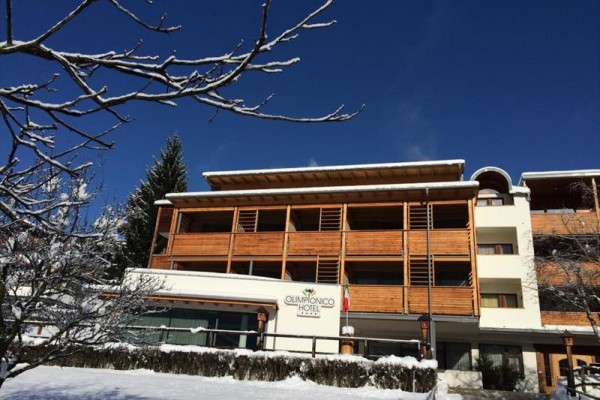 Hotel s dreveným obkladom a zasneženým okolím pod modrou oblohou.