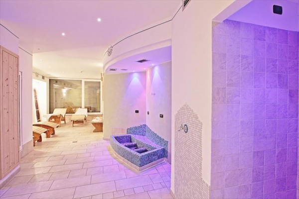 Wellness priestor s ležadlami a osvetlenými stenami.