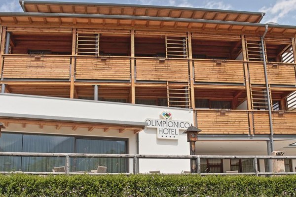 Moderná hotelová budova s drevenými balkónmi a nápisom 