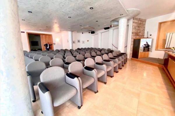 Prázdna konferenčná miestnosť s radami šedých sedadiel.