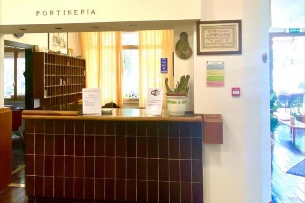 Recepcia s pultom a kvetom v kvetináči, nápis 
