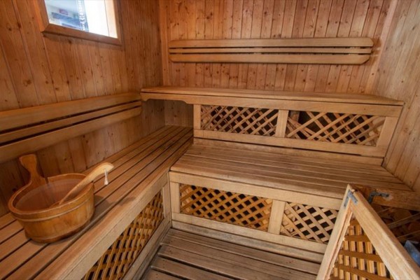 Drevená sauna s lavicami a vedrom na vodu.