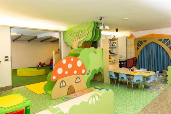 Farebná herňa s detskými hračkami, stolíkmi a dekoráciami pripomínajúcimi huby a stromy.