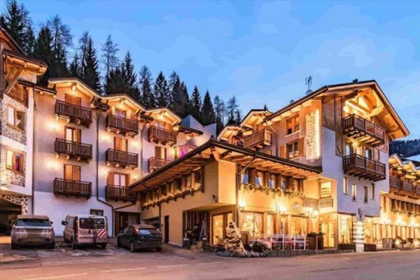 Horský hotel s drevenými balkónmi osvetlený v zimnej krajine.