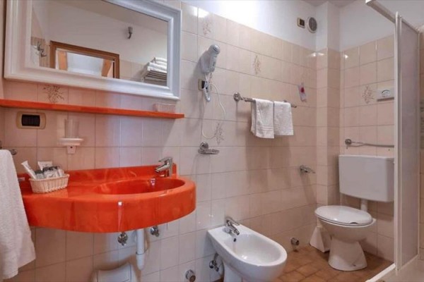 Kúpeľňa s oranžovým umývadlom, bidetom a toaletou.