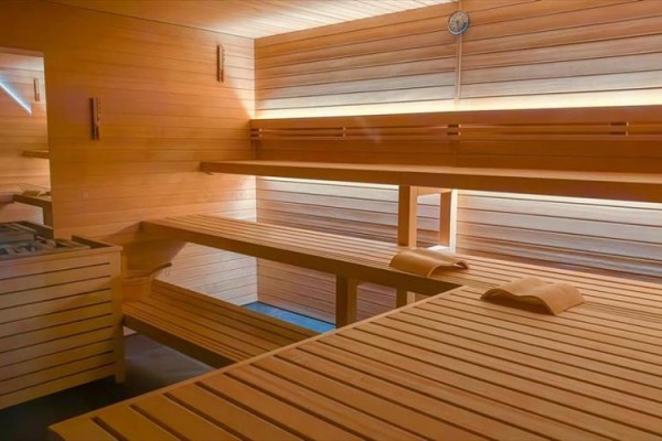 Drevená sauna s lavicami a teplomerom na stene.