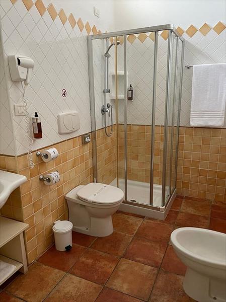 Kúpeľňa s toaletou, bidetom a sprchovacím kútom na dlažbe.