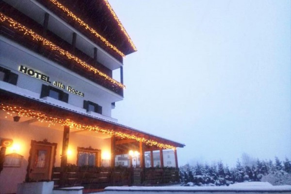 Hotel ozdobený sviatočnými svetlami s výhľadom na zasneženú krajinu.