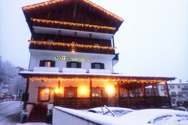 Trojposchodový hotel ozdobený svetelnými reťazami, zasnežená krajina.