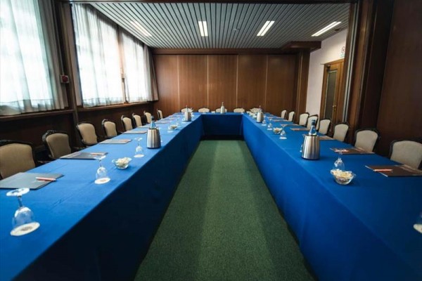 Konferenčná miestnosť s usporiadaním stola do tvaru písmena U s modrými obrusmi.