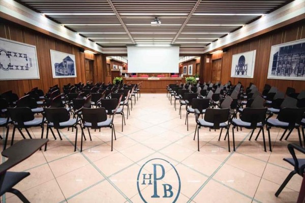 Konferenčná miestnosť s premietacím plátnom a organizátorským stolom.