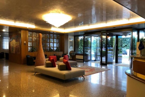 Elegantná hotelová lobby s pohodlnými pohovkami a sklenenými vstupnými dverami.  