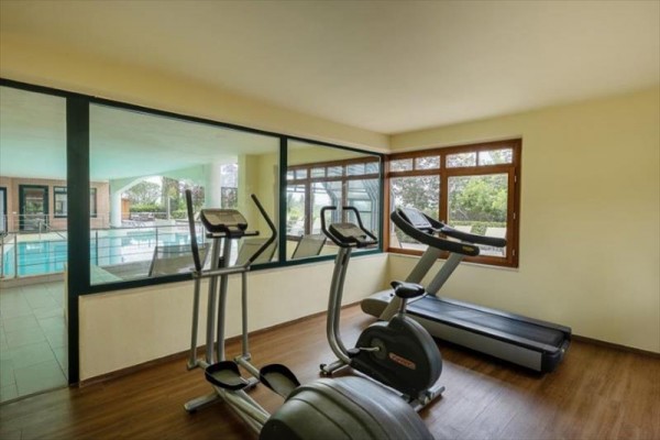 Miestnosť s fitness zariadením a výhľadom na krytý bazén.