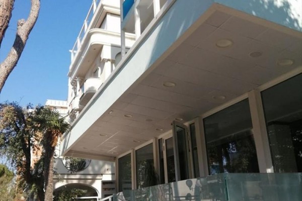 Moderná budova s presklenou fasádou a balkónmi.