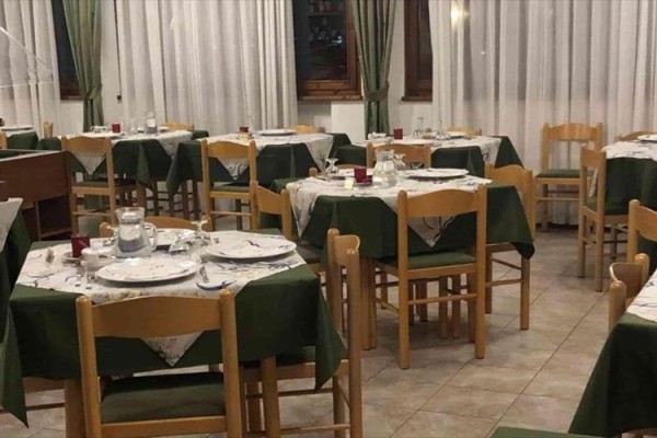 Reštaurácia s drevenými stoličkami a zelenými obrusmi.