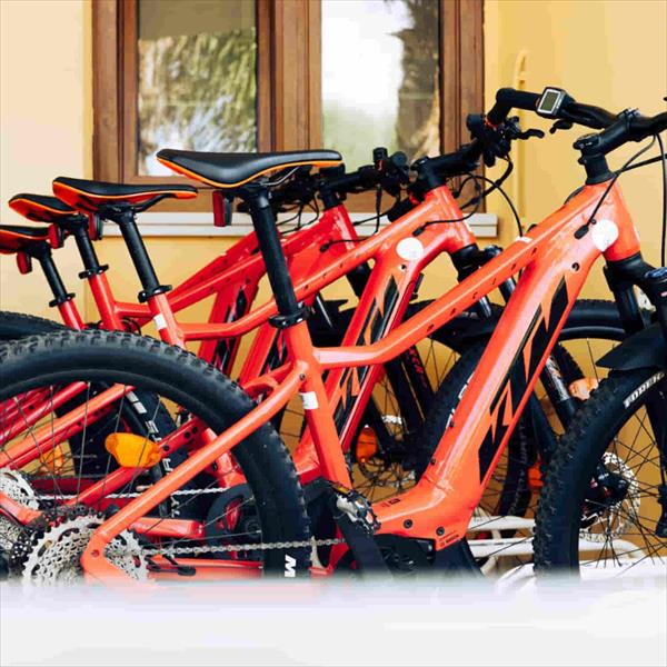 Červené bicykle zoradené vedľa seba pred domom.
