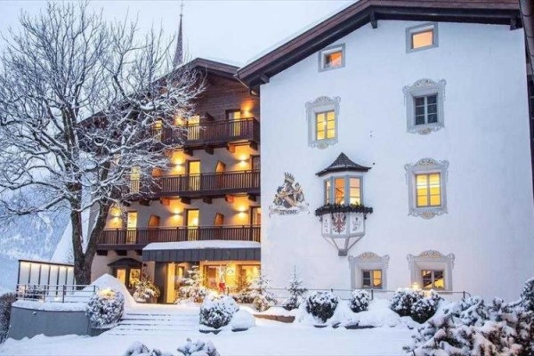 Zasnežený hotel s rozsvietenými oknami a ozdobenou fasádou.