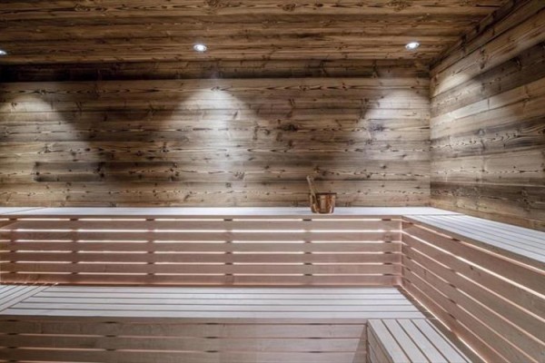 Drevená sauna s lavičkami a vedrom.