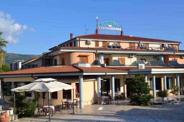 Hotel s terasou a vonkajším posedením pod slnečníkmi.