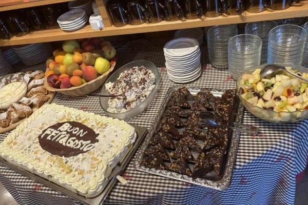 Dezertný bufet s tortou, ovocím a čokoládovými zákuskami na oslave Ferragosto.  