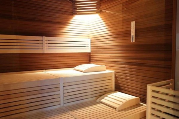 Drevená sauna s lavicou a vankúšmi osvetlená zhora.