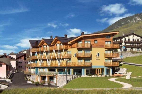 Hotel s dreveným obkladom a balkónmi v horskej krajine.
