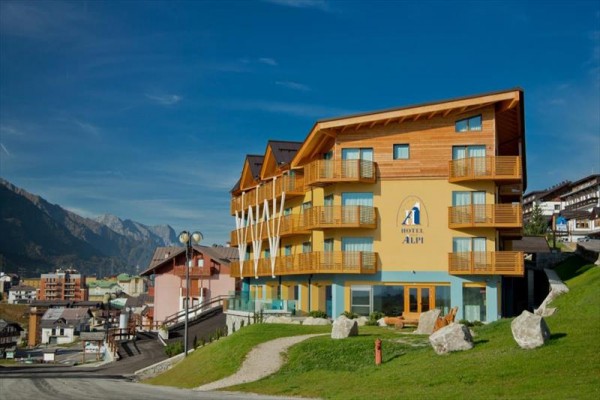 Drevený hotel na svahu s výhľadom na horskú dedinu a hory.