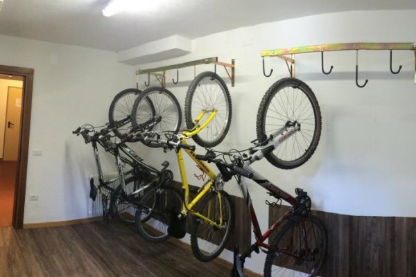 Cyklistická miestnosť s piatimi bicyklami zavesenými na stene.