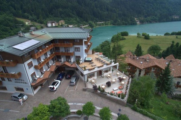 Hotel s terasou a parkoviskom pri jazere v horskej krajine.
