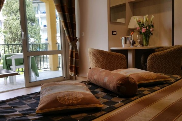 Interiér hotelovej izby s posteľou a balkónom vedúcim von.
