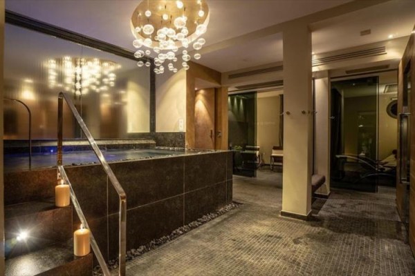 Luxusný wellness interiér so schodmi do vírivky a moderným osvetlením.