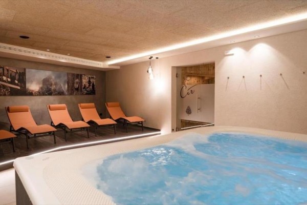 Vírivka a oranžové ležadlá v modernej relaxačnej miestnosti.
