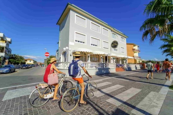 Dvaja ľudia vedú bicykle cez prechod pri budove s nápisom 